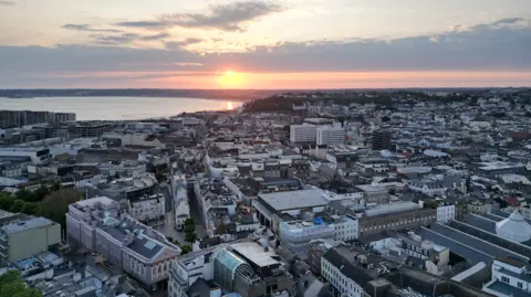 An aerial view of sunset over St Helier, with the ocean in the background.