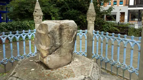 Getty Images An ancient block of stone surrounded by railings in a suburban London street. 