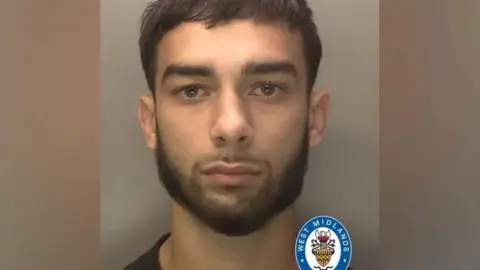 West Midlands Police A mugshot of Dolars Aleksanders, 21, with a grey background. He has short dark hair, swept to the right side of his face with a short dark beard. The collar of a dark top is just visible.