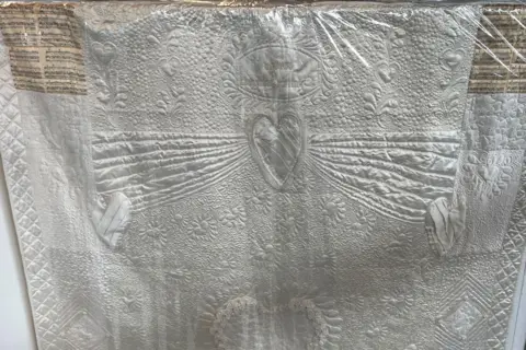 Jon Wright/BBC A white, highly embroidered wedding dress which has been turned into a quilt 