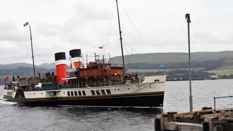 the paddle steamer in the water as it approaches a pier