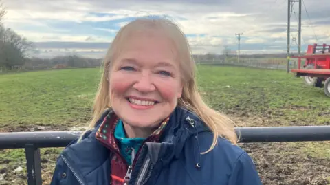 Photograph of Carole Dunnington from Platt Bridge in Wigan. The 62 year-old is pictured in front of a gate and a field.