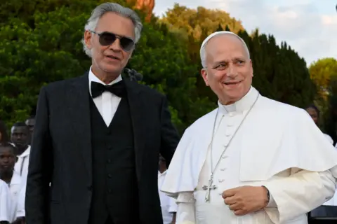 Getty Images Pope Leo XIV in his traditional robes. Bocelli is stood next to him in aviator sunglasses and a black tuxedo.
