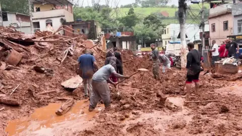 Reuters A man digs mud with a shovel while several other people also look on and help