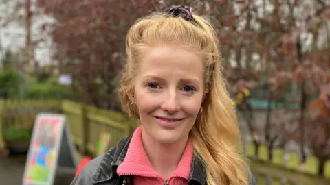 Hannah Spencer, a young woman with long hair tied in a pony tail, smiles in a local park