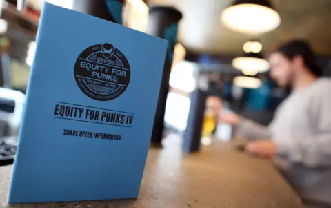 Getty Images A blue Equity for Punks IV share offer booklet sitting on a table in a bar