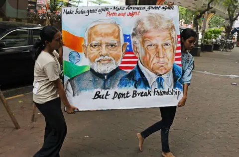 LightRocket via Getty Images Two Indian students carry a poster of Trump and Modi outside their school in Mumbai.