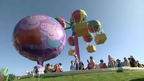 A balloon with peppa pig on in front of a hot air balloon themed ride.