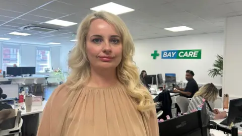 A woman with long blonde hair wearing a peach top