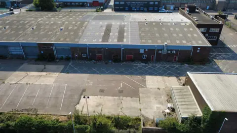 Suffolk County Council An aerial image of a large brick building. On the edge of the image are some trees and overgrowth. 
