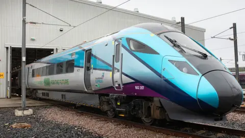 Hitachi Rail's test tri-mode train on the tracks as it leaves the company's factory in Newton Aycliffe in England. On the side the words "fully charged for the future" are written.