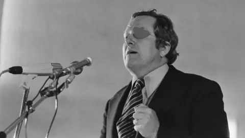 Getty Images Front Kandidat nasional untuk pemilihan presiden Prancis tahun 1974 Jean-Marie Le Pen, mengenakan penutup mata, menyampaikan pidato pada rapat umum pemilihan pada tanggal 26 April 1974 di Colmar