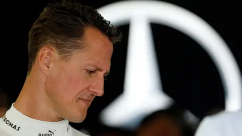 Reuters foto Schumacher 2012 di profil, memandang ke bawah dengan logo Mercedes di belakangnya. 