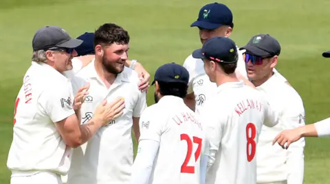Tom Norton is congratulated by his Glamorgan team-mates