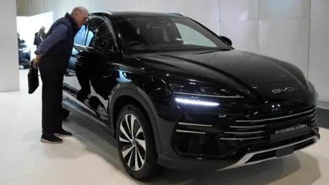 A man inspects a black BYD Seal U exhibited at car show in London