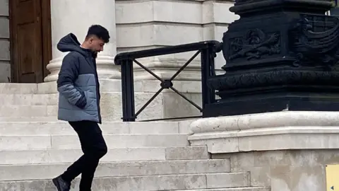 A man in a grey coat walking on court steps 