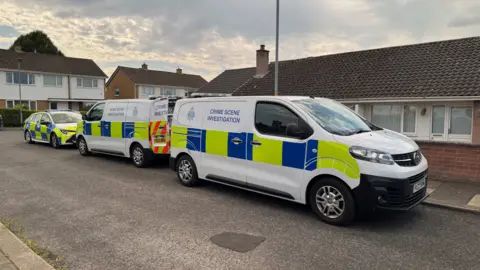 Two crime scene investigation vans and a police car outisde a bungalow on Whinlatter Way in Carlisle. 