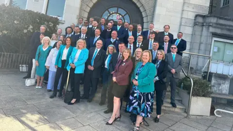LDRS A group of people standing on the steps outside Kent County Hall. Many are wearing blue jackets and all are looking at the camera and smiling.