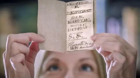 PA Media Woman out of focus peering up a tint book, the size of the palm of your hand
