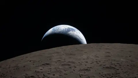 Earth poking out from behind the cratered surface of the Moon.
