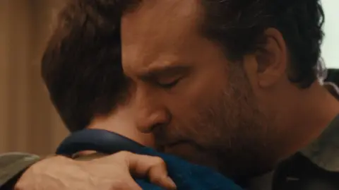 John Lewis A close-up of a father and a son embracing in a hug. 