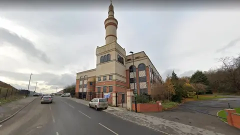 A large building with an ornate tower on the side of a road.