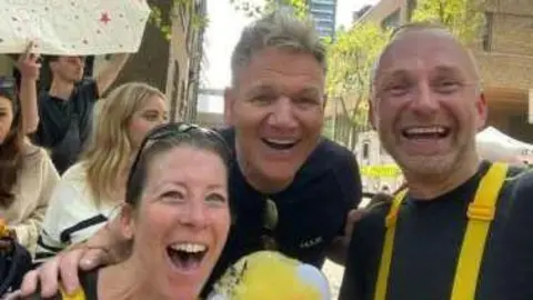 Woodlands Meed Tom Brown in a selfie with another runner and with Gordon Ramsey in between them. They are all looking at the camera and smiling.