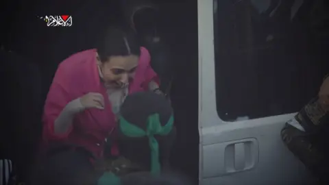 Reuters An excited Romi Gonen wearing a pink shawl steps out of a white Hamas van 