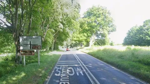 Google Single carriageway road with road sign to the left - it is a bright, sunny day.