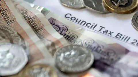 A pile of notes and coins, on top of a piece of paper saying council tax bill
