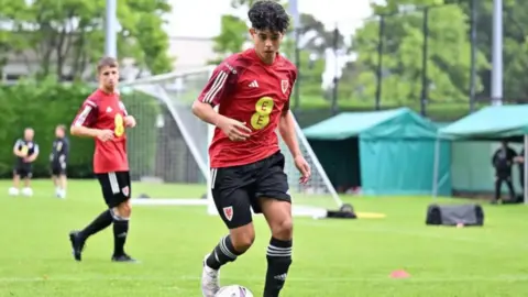 Enzo Romano, a teenage boy with black curly hair in a Wales kit
