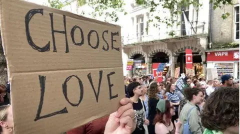 Robby West/BBC 'Choose Love' placard held up by protester