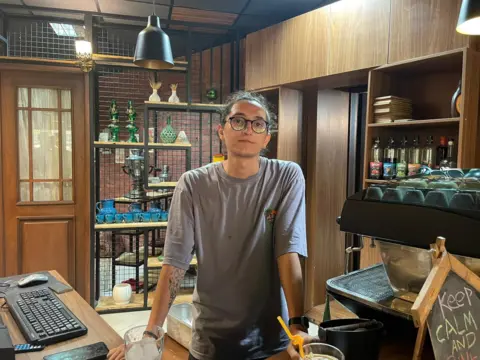 An Iranian man standing behind a counter in a shop