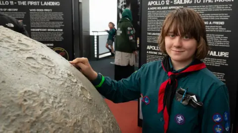 Martyn Milner A boy scout has his hand on a large scale model of the moon