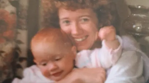 Police Scotland Young woman with red curly hair, smiling and holding a baby