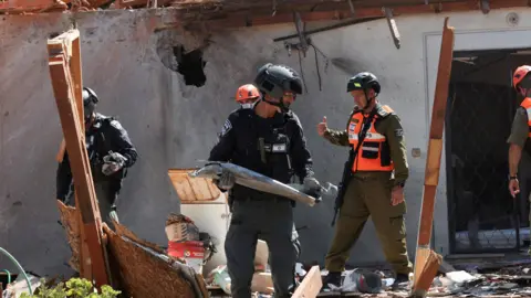 Reuters Israeli soldiers and police remove debris from a home in northern Israel that was damaged by a Hezbollah rocket launched from Lebanon, (24 September 2024)