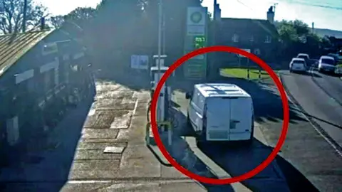 White van parked on petrol forecourt next to fuel pump  