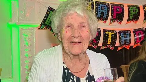 Hilda Jackson holding a glass of champagne at her 105th birthday rave in Derbyshire