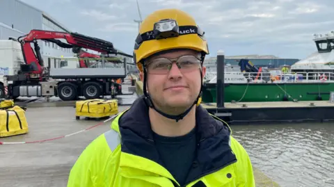 Ben Schofield/BBC Hayden Wright standing on the quayside at the Port of Lowestoft