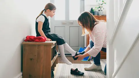 Getty Images Mother puts shoes on child - stock shot