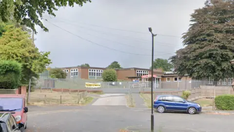 A single-storey flat-roofed brick school building at the end of a cul-de-sac