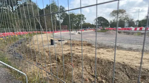 Dug up, dry earth is pictured behind a metal fence. 