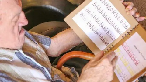 Ashbrook Court Care Home Joe Miechielsens looking at a workbook