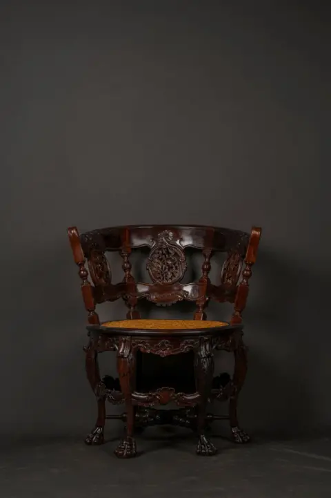 Vivek Gandhi A teakwood chair with a cane seat, curved backrest and six legs.