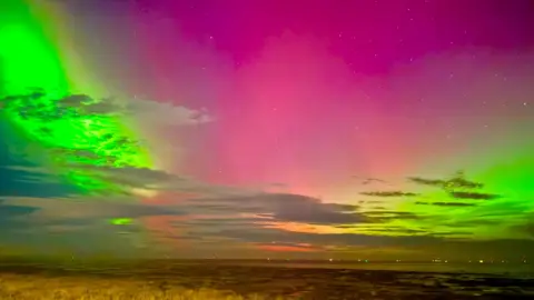 BBC Weather Watchers / SJMC bright almost neon green and purple colours in the sky with the northern lights.