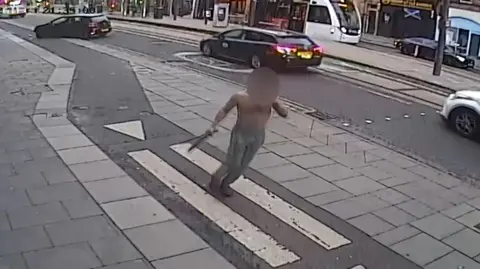 A blurred image of a bare chested man apparently holding two knives