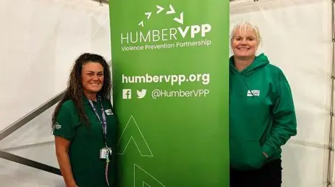 Shona Nicholson and Helen Longstaff dressed in green fleece tops and black bottoms. 