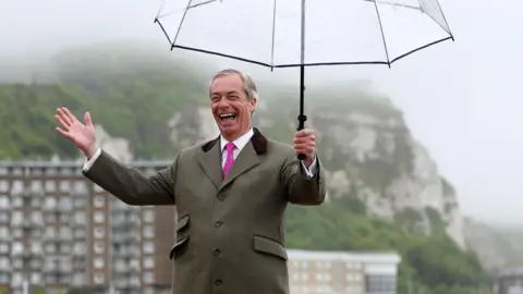 EPA Nigel Farage pictured grinning and holding a see-through umbrella with the White Cliffs of Dover in the background