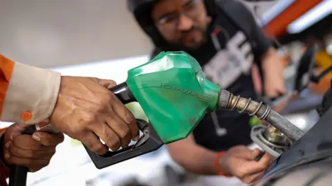 An attendant refuels a motorcycle at a station in India