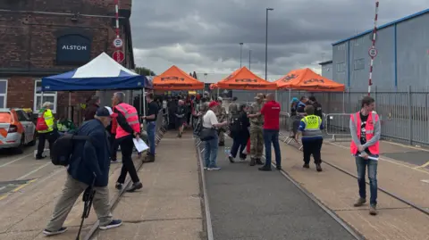 People entering the Greatest Gathering with staff nearby
